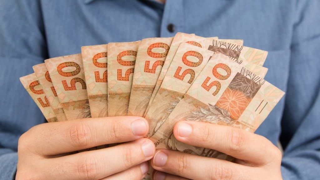 bxblue - homem com cédulas de dinheiro nas mãos - solicitar empréstimo consignado para servidor público online
