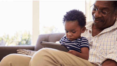 homem sentado no sofá com criança e tablet em mãos - acesso online meu inss