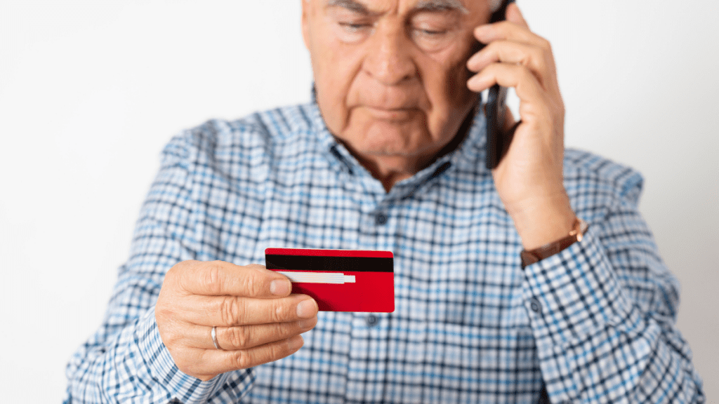 desbloquear o cartão de crédito consignado pessoa de terceira idade com telefone e cartão nas mãos