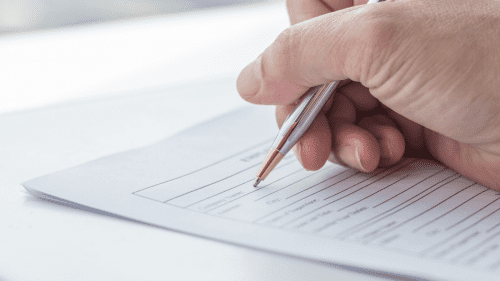 bxblue - formulários e requerimentos do INSS - pessoa preenchendo documento com caneta nas mãos