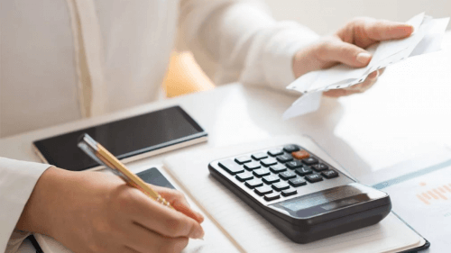 adiar as parcelas do empréstimo consignado - pessoa fazendo cálculo, com calculadora, contas, papel