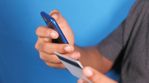 prevenção a fraudes - homem com celular e cartão nas mãos