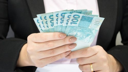 conta-salário dos servidores públicos - mãos de mulher segurando notas de dinheiro