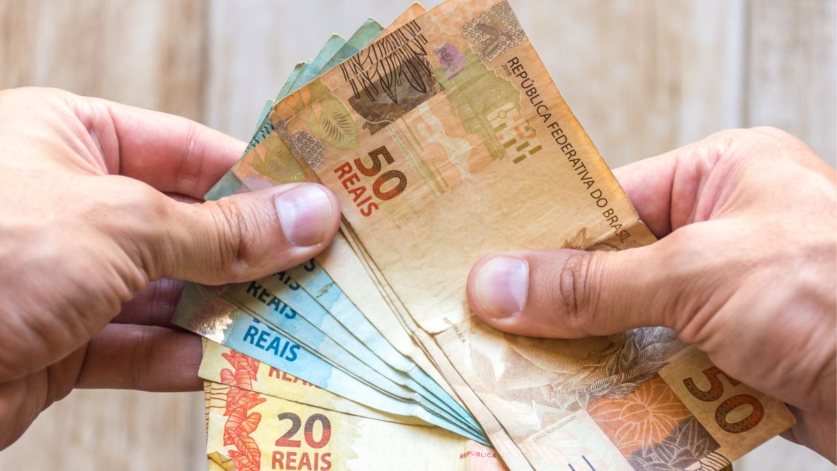 pessoa com notas de dinheiro na mão, real, moeda brasileira